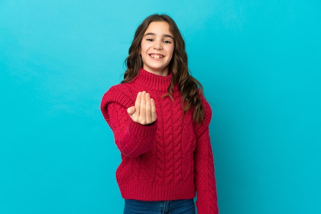 Piccola ragazza caucasica isolata su priorità bassa blu che invita a venire con la mano. Felice che tu sia venuto