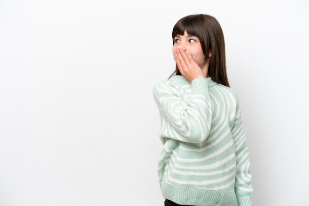 Piccola ragazza caucasica isolata su sfondo bianco che fa un gesto a sorpresa mentre guarda di lato