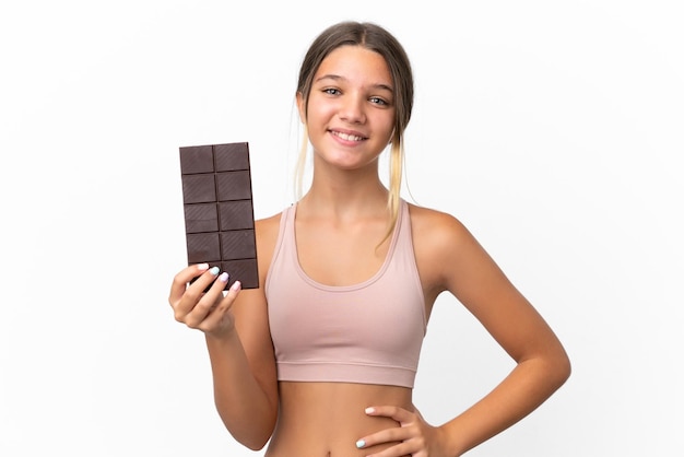 Piccola ragazza caucasica isolata su sfondo bianco che prende una tavoletta di cioccolato e felice