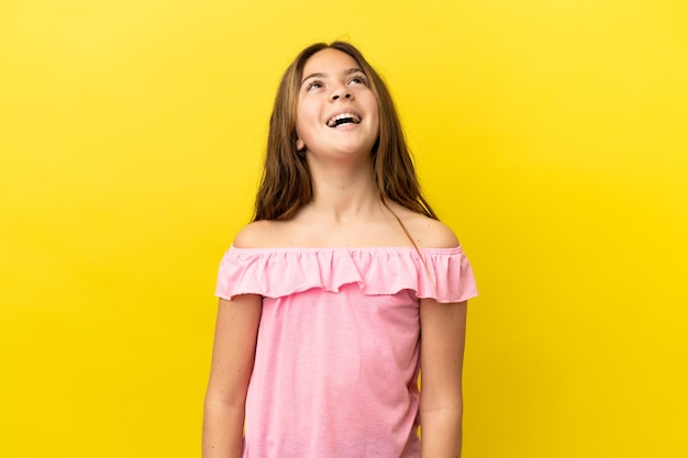 Piccola ragazza caucasica isolata su sfondo giallo ridendo