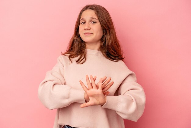 Piccola ragazza caucasica isolata su sfondo rosa che fa un gesto di rifiuto