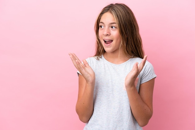 Piccola ragazza caucasica isolata su sfondo rosa con espressione facciale a sorpresa