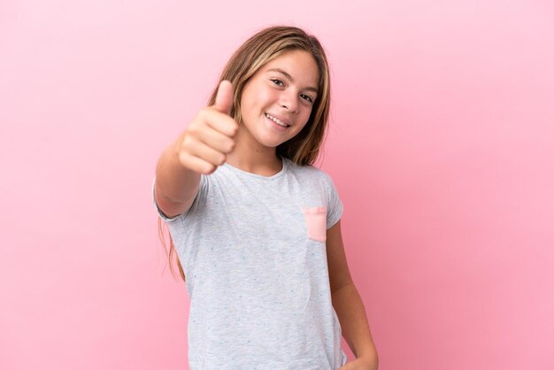 Piccola ragazza caucasica isolata su sfondo rosa con i pollici in su perché è successo qualcosa di buono