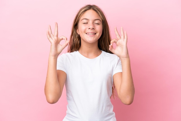 Piccola ragazza caucasica isolata su sfondo rosa in posa zen