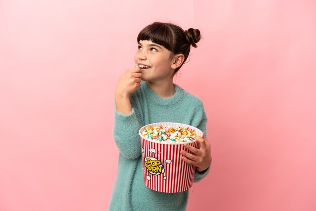 Piccola ragazza caucasica isolata tenendo un grande secchio di popcorn