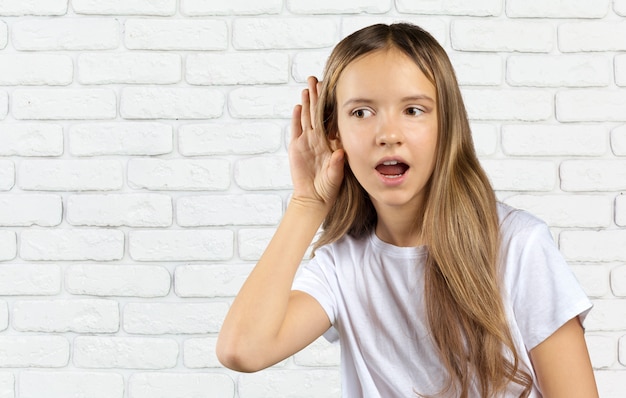 Piccola ragazza caucasica nell'azione dell'udito isolata