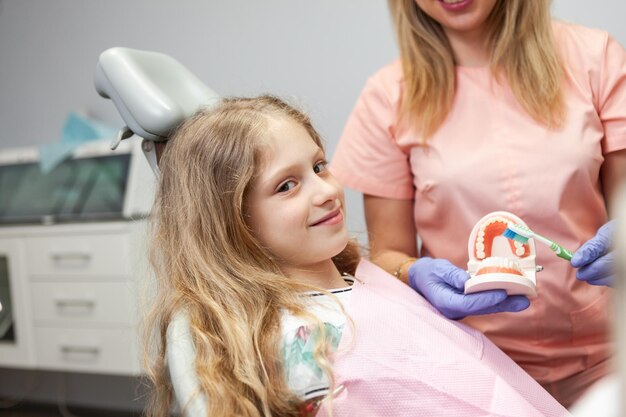 Piccola ragazza caucasica sorridente durante l'esame dal dentista nella clinica dentale