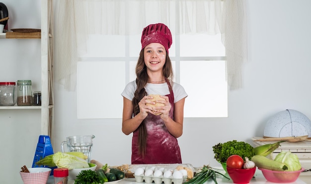 Piccola ragazza che cuoce in cucina chef bambino che cucina facendo pasta bambino prepara cibo sano a casa e indossa l'uniforme del cuoco per le pulizie e la casa aiutando lo sviluppo dell'infanzia chef professionista