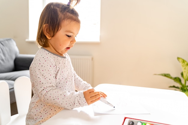 Piccola ragazza che disegna con il pennarello a casa