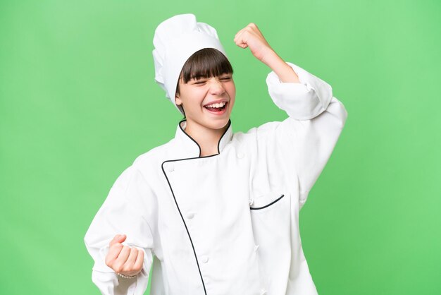 Piccola ragazza chef caucasica su sfondo isolato che celebra una vittoria