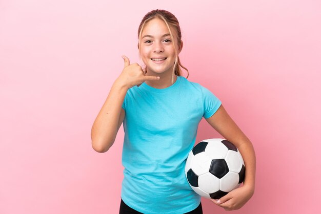 Piccola ragazza del giocatore di football isolata su fondo rosa che fa gesto del telefono. Richiamami segno