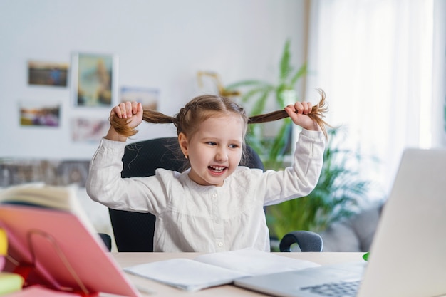 Piccola ragazza di divertimento che usando i concetti digitali di e-learning di un computer portatile