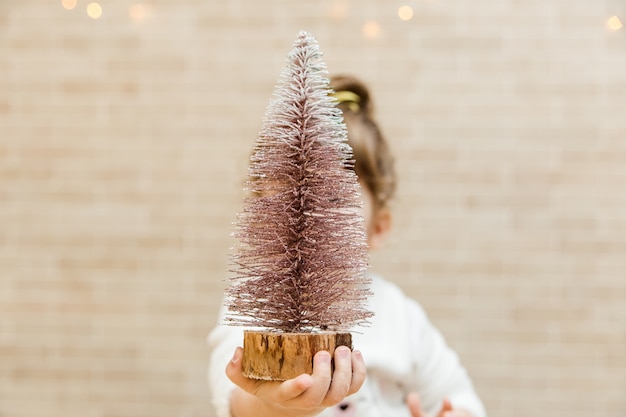 Piccola ragazza divertente con l'albero di Natale. Stile minimalista.