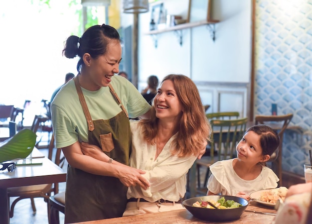 Piccola ragazza e sua madre a pranzo e incontrano la loro amica cameriera vietnamita in un caffè