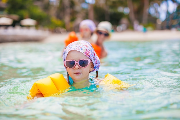 Piccola ragazza felice che spruzza in acqua turquiose chiara