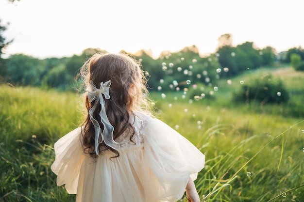 Piccola ragazza felice e bolle di sapone concetto di infanzia felice