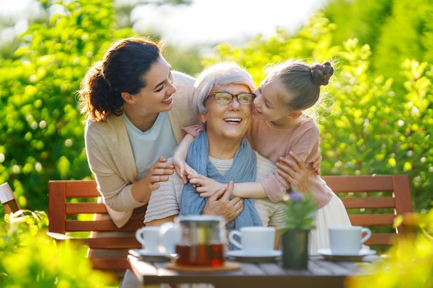 Piccola ragazza felice sua madre e nonna che bevono il tè in una mattina d'estate