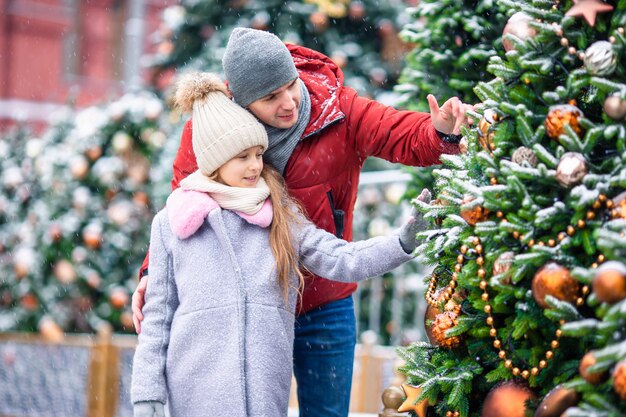 Piccola ragazza felice vicino al ramo dell'abete in neve per il nuovo anno.