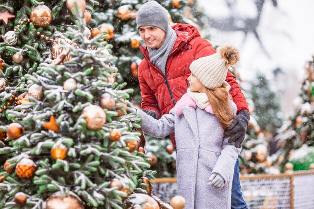 Piccola ragazza felice vicino al ramo dell'abete in neve per il nuovo anno.