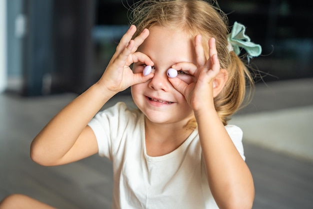 Piccola ragazza gioca con perle facendo braccialetti di perle di legno La creatività dei bambini e lo sviluppo delle abilità motorie fini