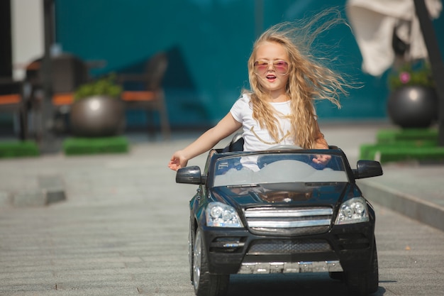 Piccola ragazza graziosa che guida un'automobile. Bambino alla guida di un'automobile. Come un adulto