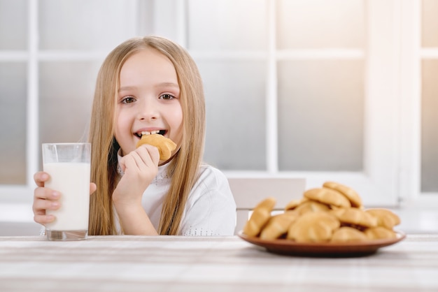 Piccola ragazza graziosa che mangia biscotto dolce.