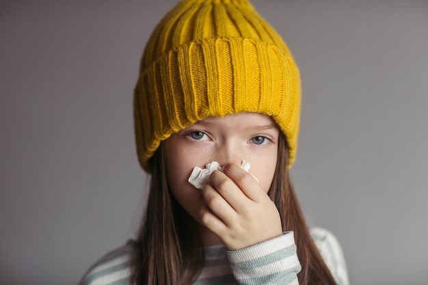 piccola ragazza malata in un cappello soffia il naso