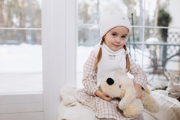 Piccola ragazza sveglia adorabile in cappello tricottato all'interno a casa