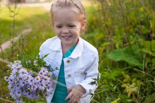 Piccola ragazza sveglia che cammina con un mazzo di fiori