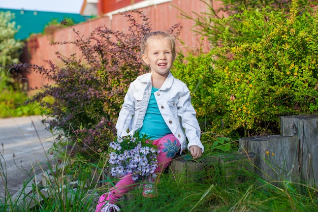 Piccola ragazza sveglia che cammina con un mazzo di fiori