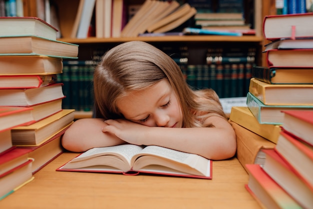 Piccola ragazza sveglia che dorme nella biblioteca