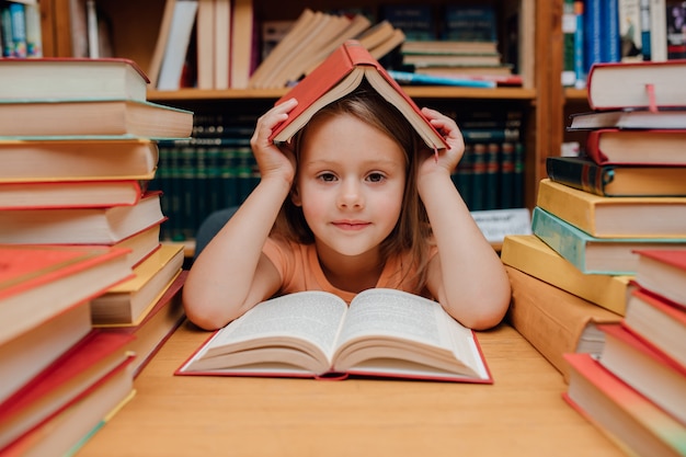 Piccola ragazza sveglia che legge nella biblioteca