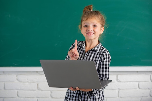 Piccola ragazza sveglia del bambino che utilizza il bambino del computer portatile che studia tramite il piccolo sistema divertente di elearning online