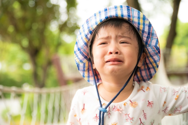 Piccola ragazza sveglia triste che grida nel giardino