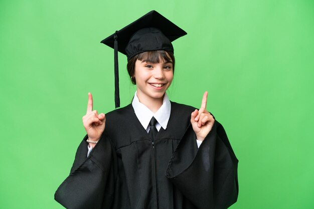 Piccola ragazza universitaria su sfondo isolato che punta verso l'alto una grande idea