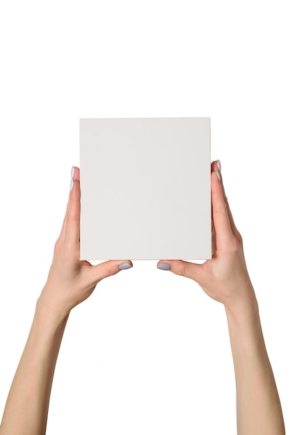 Piccola scatola di cartone bianca in mani femminili. Vista dall'alto. Isolato