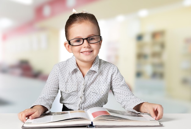 Piccola scolara con il libro sulla priorità bassa della lavagna