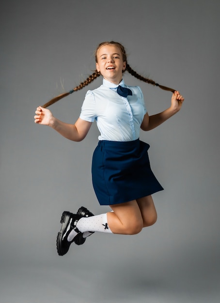 Piccola scolara con un sorriso felice. Piccola studentessa in uniforme scolastica. Studentessa carina con i capelli lunghi. Istruzione elementare. Studentessa perfetta