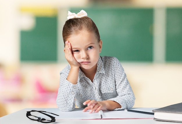 Piccola scolara triste in aula sul fondo della lavagna