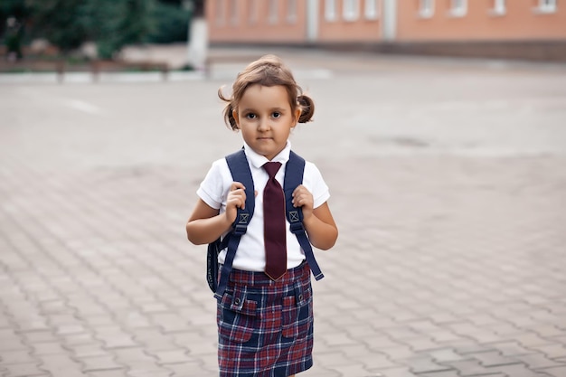 Piccola scolaretta carina in uniforme con zaino da scuola.