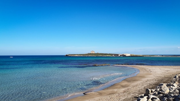 Piccola spiaggia nella città di Portopalo, Sicilia con l'isola di Capo Passero e la sua fortezza sullo sfondo