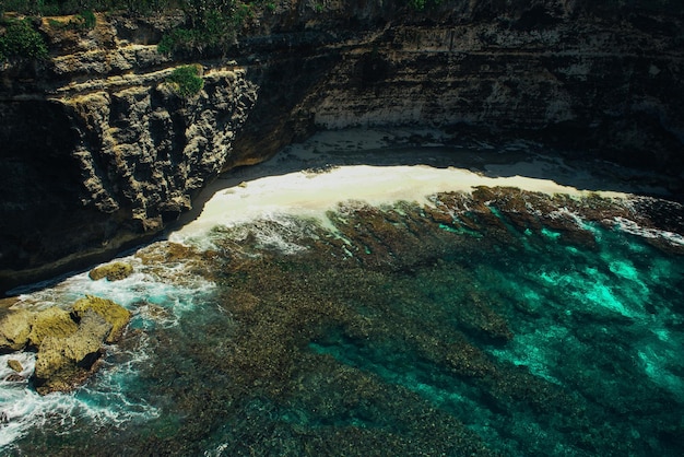 Piccola spiaggia sabbiosa davanti all'arco di pietra sul mare sulla spiaggia rotta Nusa Penida Indonesia