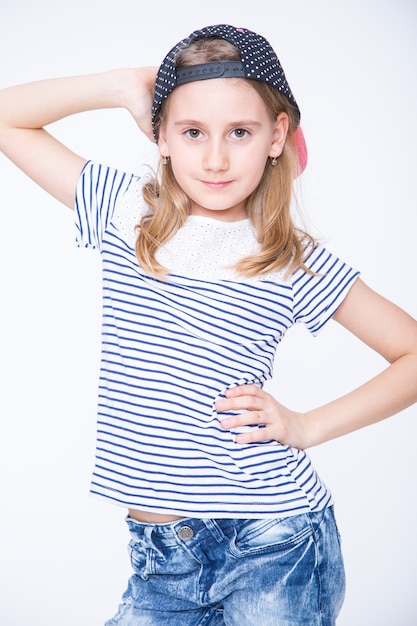 Piccola studentessa allegra con capelli biondi e berretto.