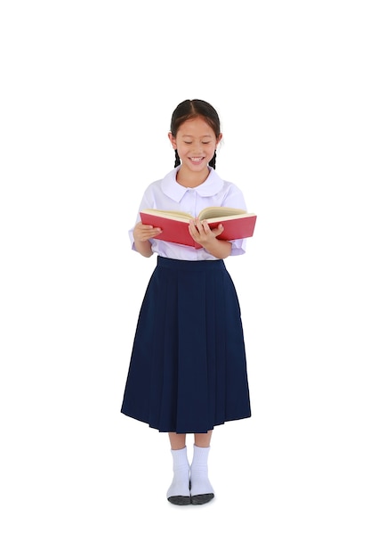Piccola studentessa asiatica allegra in uniforme scolastica tailandese in piedi con un libro di testo aperto in mano isolato su sfondo bianco per studio. Lunghezza intera