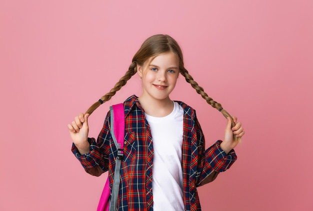 Piccola studentessa sorridente a tutta lunghezza 1013 anni in abiti casual in denim con zaino isolato su sfondo rosa ritratto in studio Il concetto di educazione dei bambini