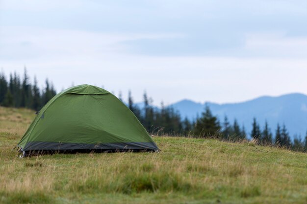 Piccola tenda turistica sulla collina erbosa della montagna. Estate in campeggio in montagna all'alba. Turismo