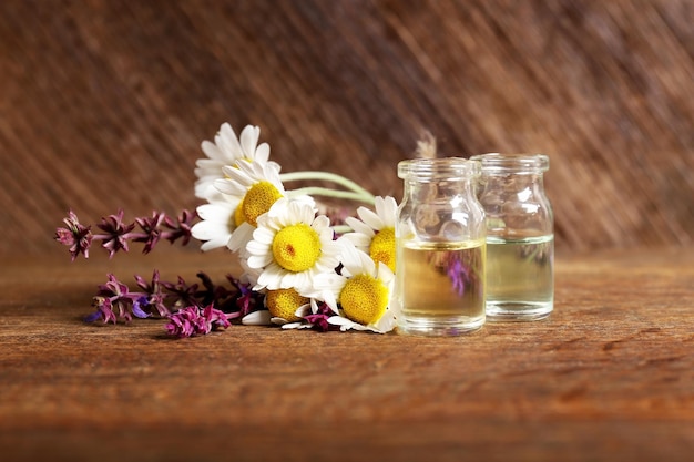 Piccole bottiglie di vetro e fiori curativi su sfondo di legno