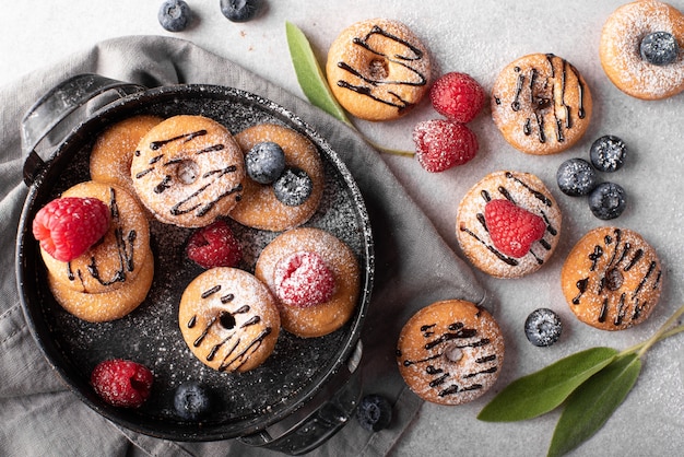 Piccole ciambelle fatte in casa con cioccolato e frutti di bosco su una vista dall'alto di lastre grigie