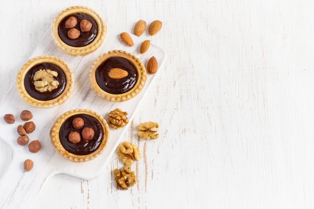 Piccole crostate al cioccolato ricco di noci su uno sfondo bianco