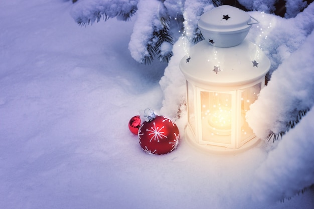 Piccole lanterne invernali all'aperto su un albero di Natale sotto la neve
